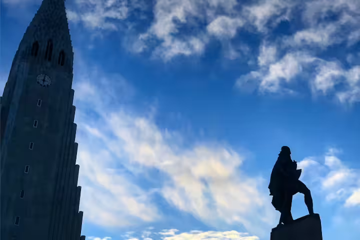 Silhouette of Leif Erikson statue with Hallgrímskirkja church tower against blue sky in Reykjavik, Iceland