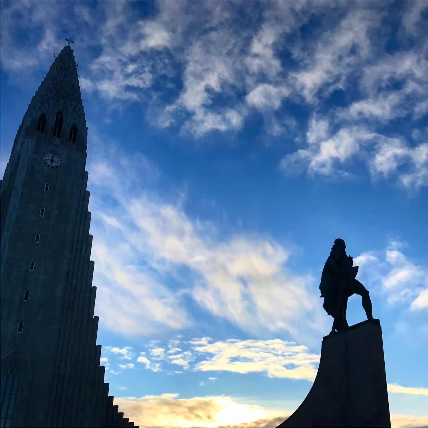 Silhouette of Hallgrímskirkja church tower and Leif Erikson statue against blue sky in Reykjavik Iceland