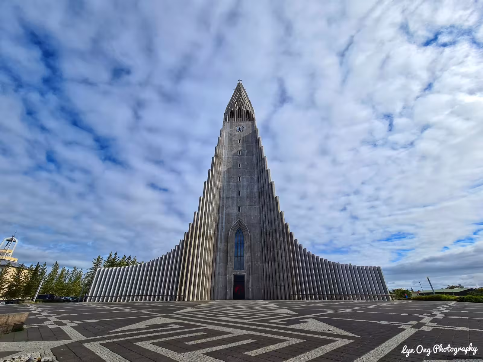 Hallgrímskirkja church dramatic concrete tower with stepped façade under cloudy blue sky in Reykjavik Iceland
