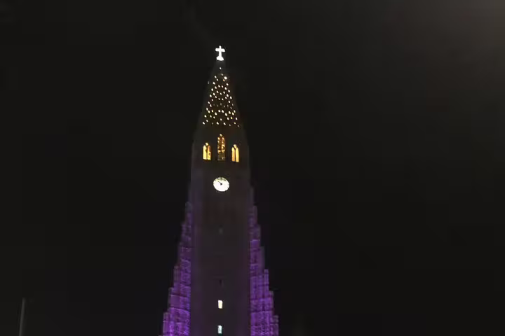 Hallgrímskirkja church tower illuminated in purple lights at night in Reykjavik Iceland