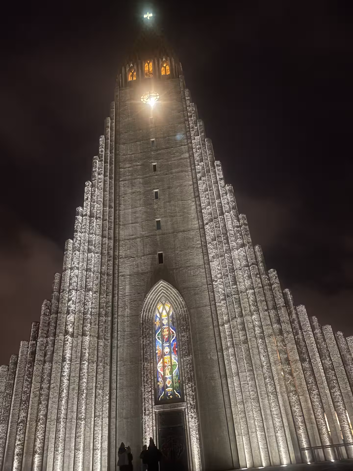 Hallgrímskirkja church illuminated at night with stained glass window and stepped concrete facade in Reykjavik