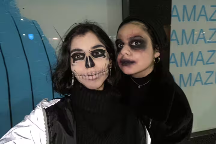 Two women wearing Halloween skeleton and zombie face paint makeup at night in Manchester
