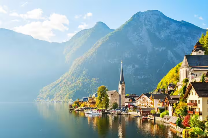 Hallstatt village with church spire along alpine lake surrounded by misty mountains