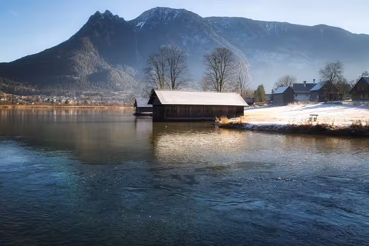 Snowy lakeside boathouse and Alpine peaks near Hallstatt on a small-group Christmas Day trip from Vienna