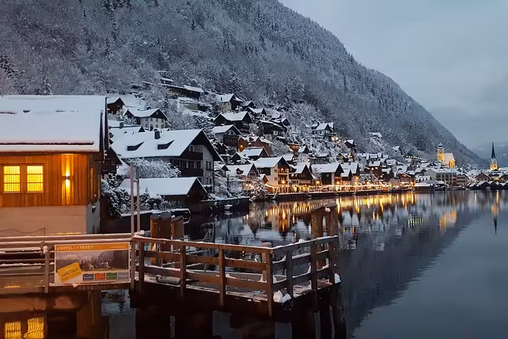 Snowy Hallstatt lakeside village at dusk with glowing lights, visited on a small-group Christmas Day tour from Vienna