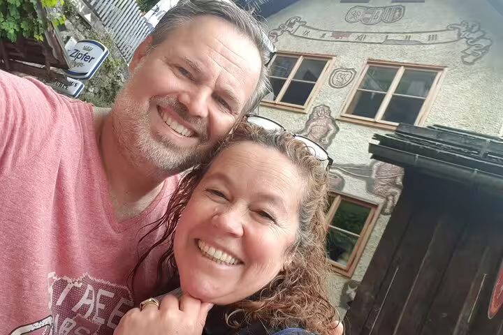 Smiling couple taking a selfie outside a traditional Austrian building in Hallstatt