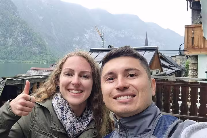 Smiling couple taking a selfie in Hallstatt with lake and mountain backdrop