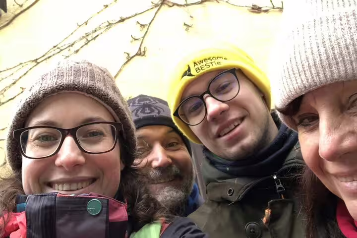 Four smiling adults in winter hats taking a selfie outdoors during a guided tour in Hallstatt