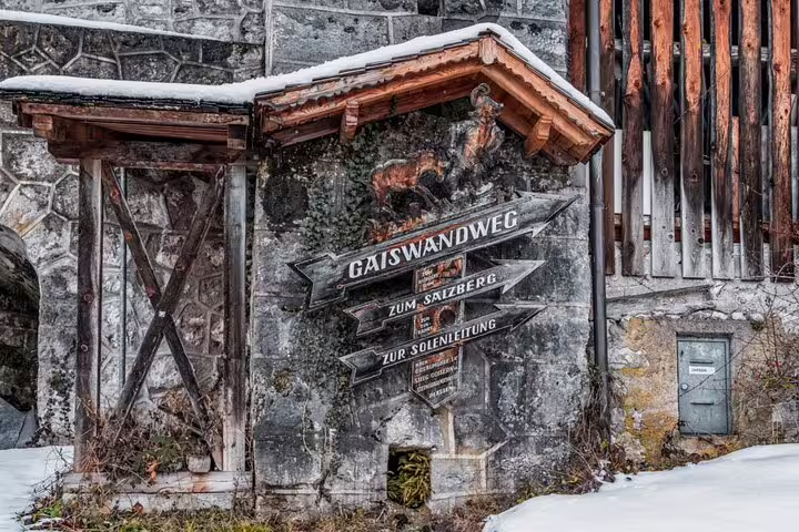 Snow-covered wooden trail signs in Hallstatt showing Gaiswandweg and Salzberg hiking directions