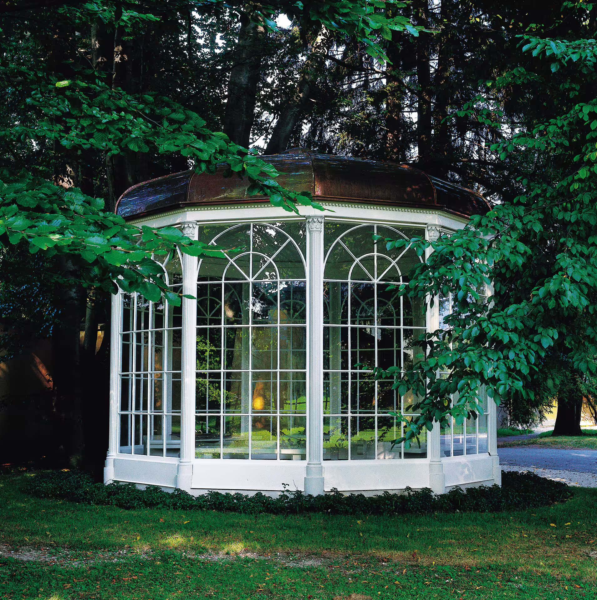 Charming glass gazebo nestled in lush greenery, featured in the Super Saver Hallstatt and Sound of Music Tour.