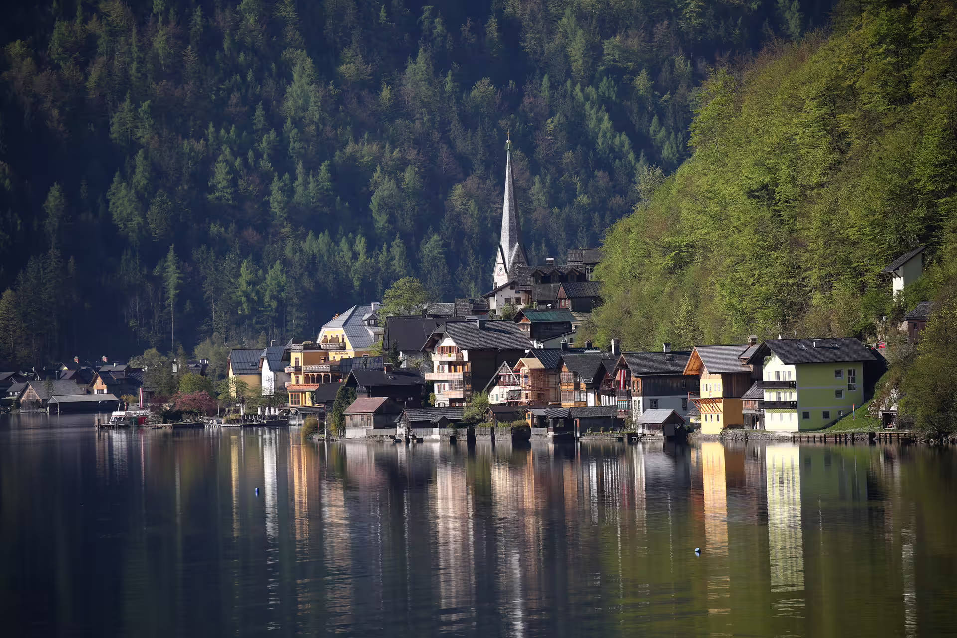 Idyllic Hallstatt village by the lake with charming houses and forested mountains, perfect for cultural tours.