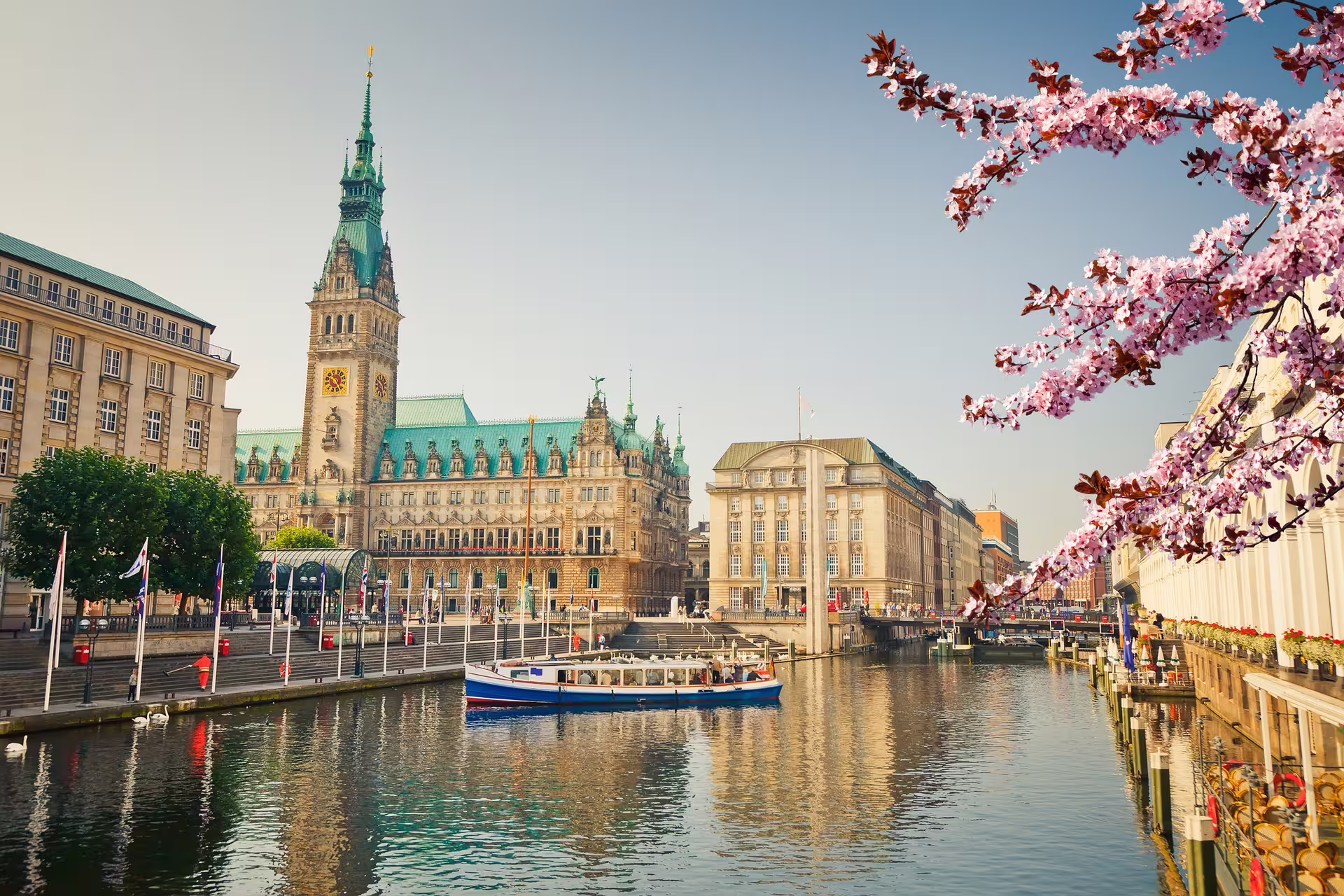 Hamburg Rathaus on Alster canal with boat and blossoms, highlight of Old Town walking tour with multilingual audioguide