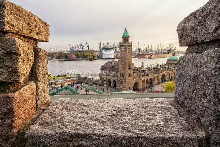 Hamburg waterfront with clock tower building, Elbe River, and cruise ships at port viewed through stone arch