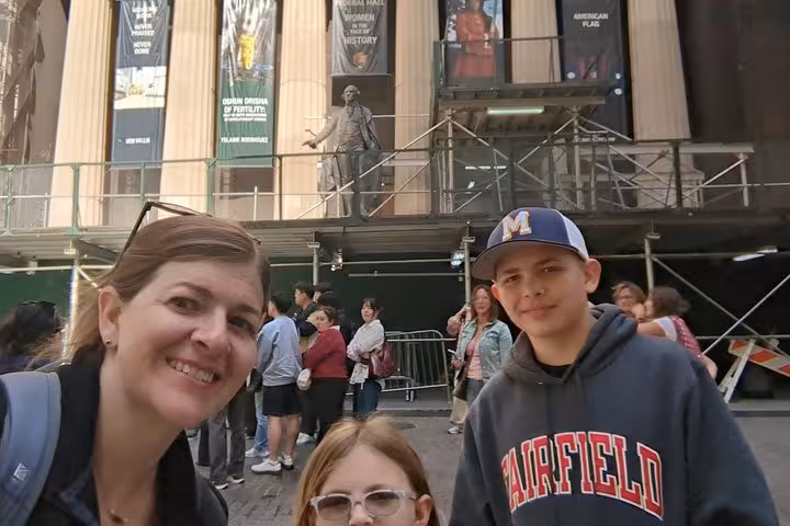 Family selfie on Hamilton self-guided walking tour in Lower Manhattan NYC with historic building and statue behind
