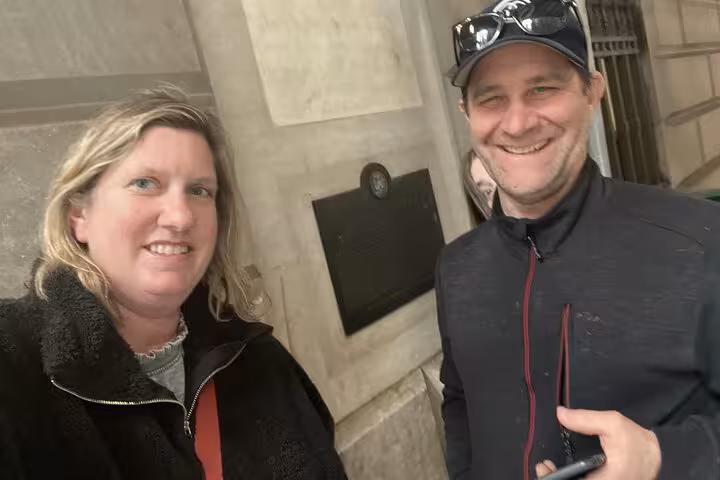Two smiling tourists on a self-guided walking tour in Lower Manhattan NYC near a historic building