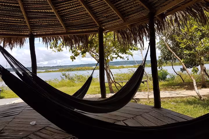 Hammocks under a thatched roof by the river, relaxing stop on Good Morning Amazon 1-night jungle stay