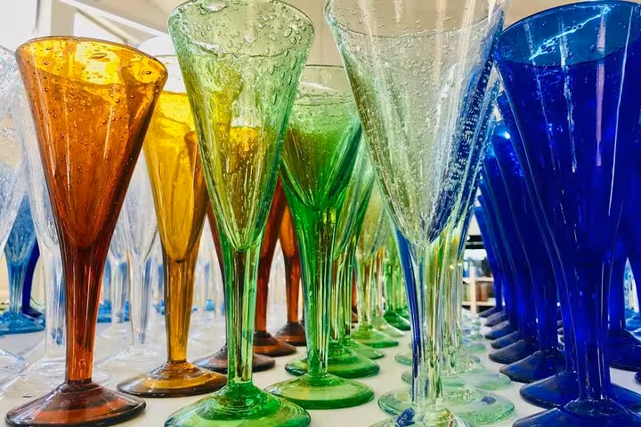 A colorful array of handcrafted glass goblets displayed in an art gallery during a private tour.