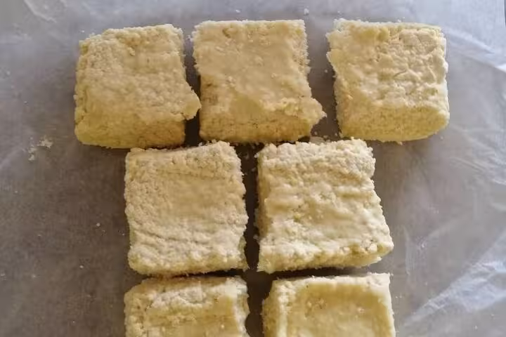 Freshly cut bars of handmade olive oil soap set on parchment paper, showcasing their natural texture.