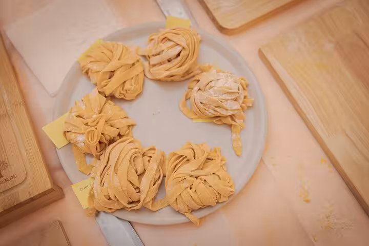 Handmade pasta nests on a plate during a cooking class in Rome's Piazza Navona, showcasing Italian culinary artistry.