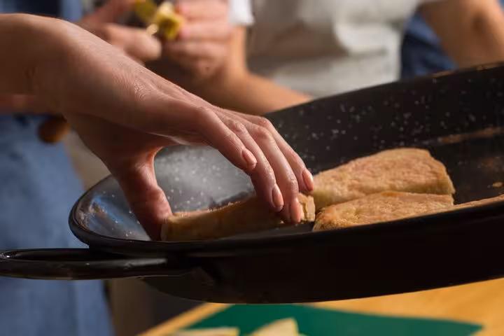 Close-up of hands preparing traditional Spanish tortillas during a tapas cooking class in Barcelona.