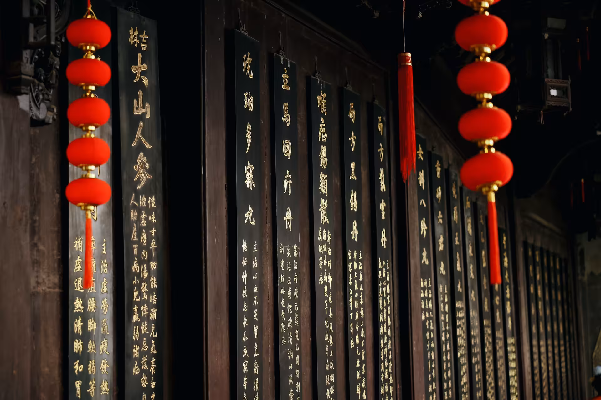 Traditional Chinese calligraphy on dark panels with vibrant red lanterns hanging, showcasing cultural heritage in Hangzhou.