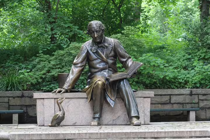 Bronze statue of Hans Christian Andersen reading a book with a duck sculpture in Central Park NYC