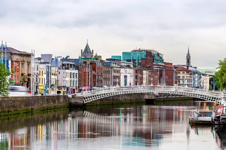 Ha'penny Bridge over River Liffey with colorful Dublin old town buildings reflected in calm water