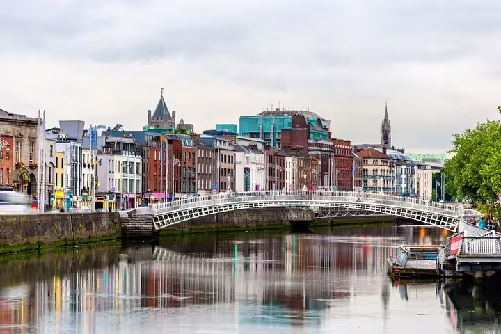 Ha'penny Bridge over River Liffey with Dublin city buildings reflected in calm water
