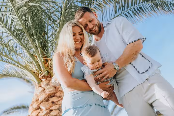 Happy family with baby enjoying a sunny day under palm trees in Analipsi.