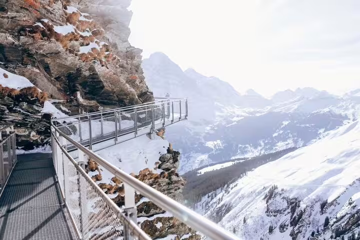 Scenic cliffside walkway with stunning views of snow-covered peaks on a Harder Kulm day trip.