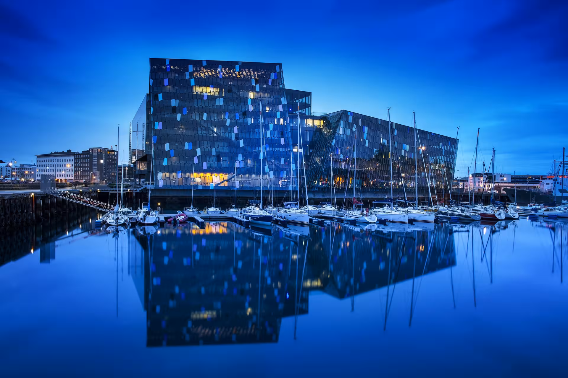 Stunning view of Harpa Concert Hall reflecting in Reykjavik harbor at twilight on Iceland 6-Day Stopover Tour.