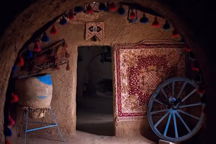 Inside a Harran mud house with woven rugs and wooden cart wheel, cultural highlight on Sanliurfa 2-day tour