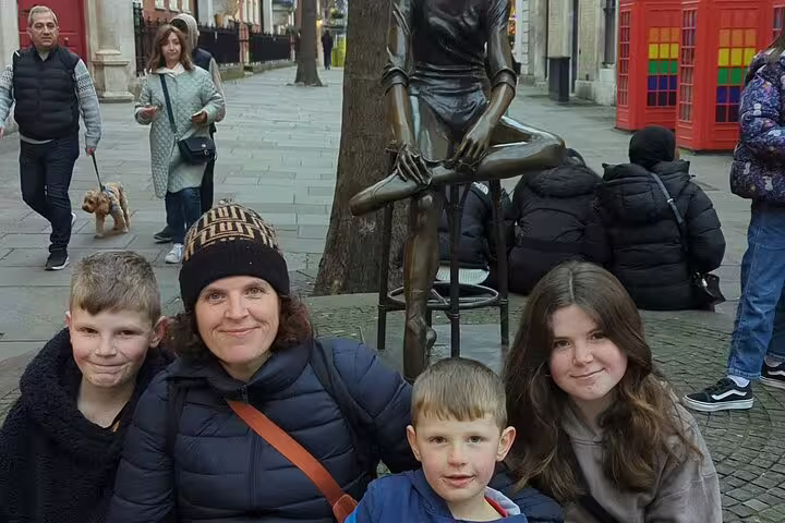 Family posing with bronze statue on Harry Potter walking tour in London street