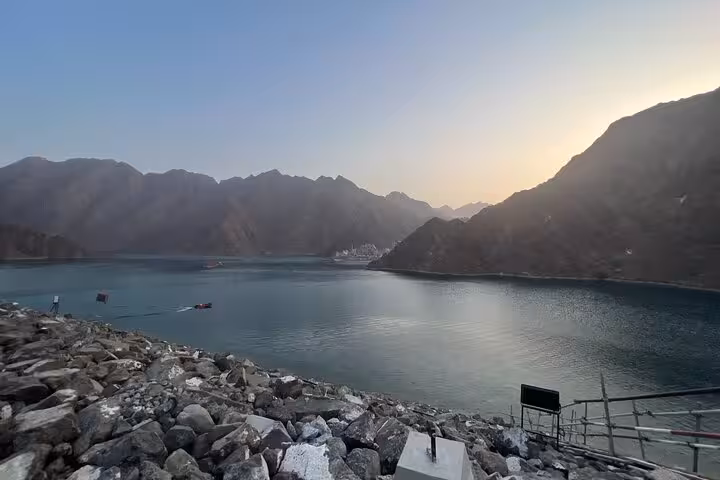 Sunset view at Hatta Dam with calm turquoise water and rugged mountains, key stop on a private full-day tour