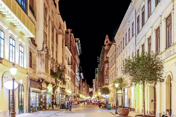 Illuminated Budapest pedestrian street at night with historic buildings and glowing lampposts