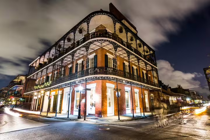 Ornate iron balconies of a historic French Quarter building illuminated at night in New Orleans