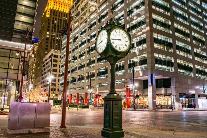 Historic double-faced street clock in downtown Houston at night with illuminated skyscrapers