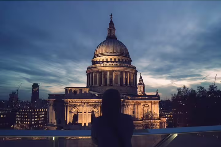 Silhouette of person gazing at illuminated St Paul's Cathedral at dusk in London