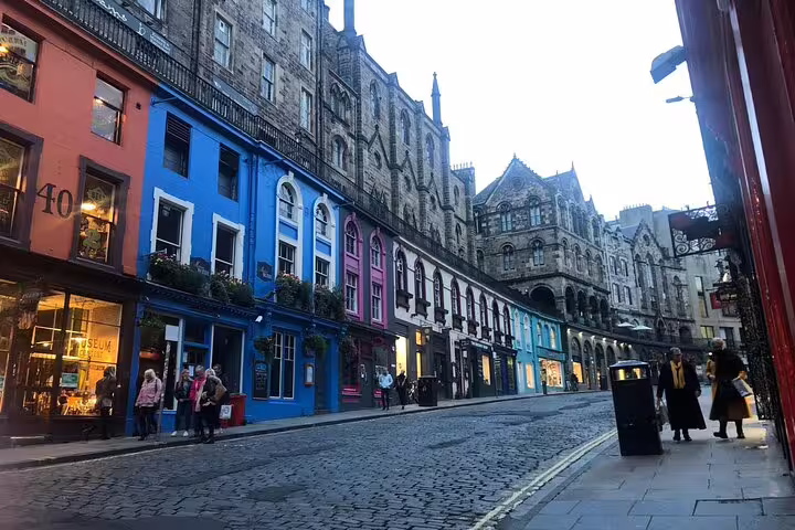 Colorful historic buildings on cobblestone Victoria Street Edinburgh at dusk with pedestrians