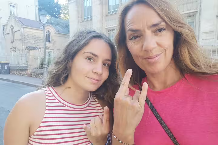 Two women smiling and posing with raised fingers on a walking tour in Montpellier, France