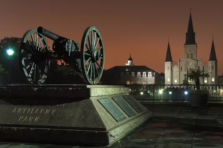 Artillery Park cannon at night with St. Louis Cathedral illuminated in New Orleans French Quarter