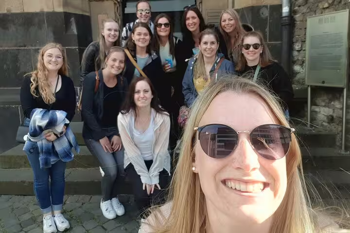 Group of women posing for a selfie on stone steps during a haunted walking tour in Cologne