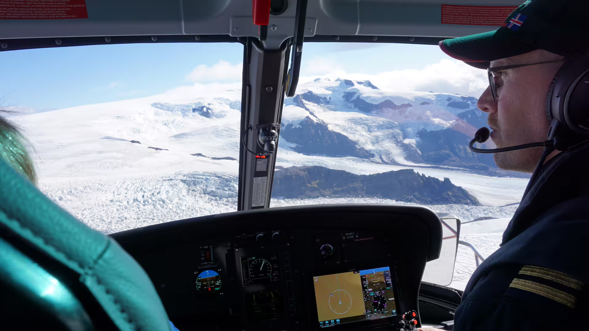 Pilot flying helicopter over Vatnajokull glacier icefield in Iceland with cockpit instruments visible