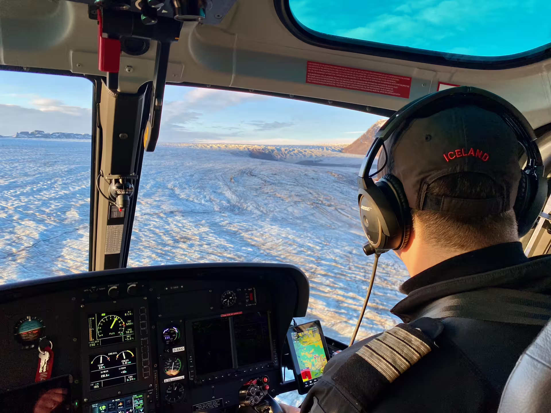 Helicopter pilot flying over Skaftafell glacier in Iceland wearing Bose headset and captain uniform