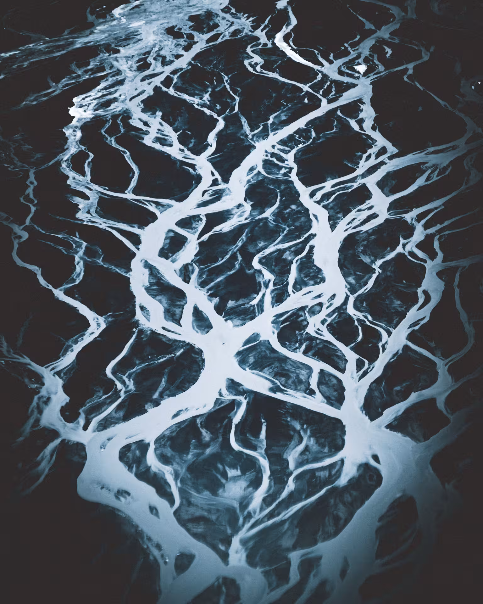 Aerial view of braided glacial river channels crossing black sand plains in Iceland