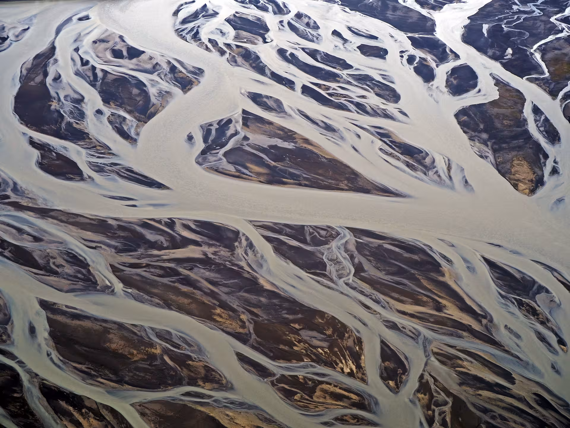 Aerial view of braided glacial river channels over black sand plains in Iceland