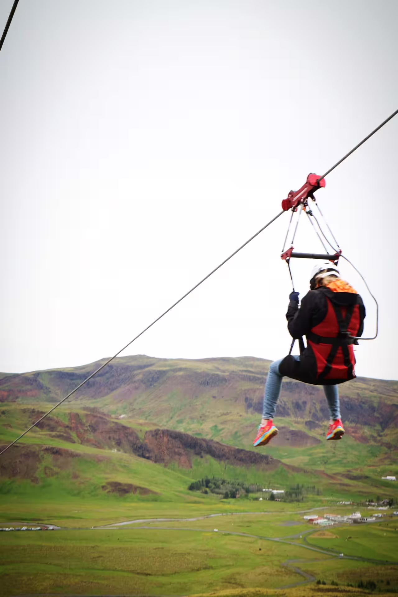 Thrill-seeker enjoys a zipline adventure against a blue sky, paired with hands-on geothermal exploration at Hellisheidi Exhibition.