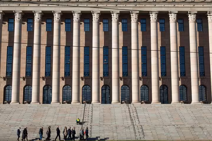 Visitors explore the steps of Helsinki's Parliament House, a key highlight on the sociologist-led walking tour.