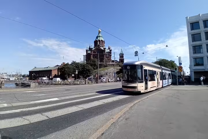 Helsinki tram passes by the iconic Uspenski Cathedral under a clear sky during a sociologist-led walking tour.