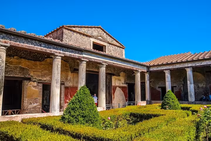 Well-preserved Roman courtyard in Hercolaneum with columns and hedges, illustrating ancient residential architecture.